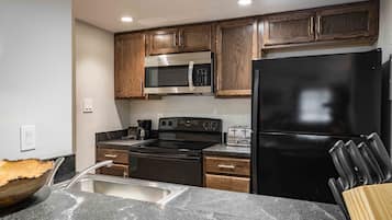 A modern kitchen with wooden cabinets, stainless steel appliances, and a granite countertop.