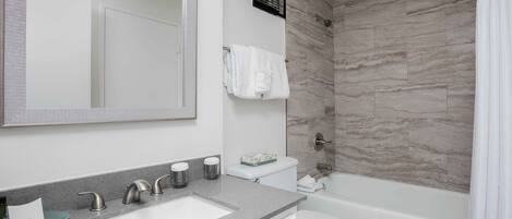 Een moderne badkamer met een grote spiegel, een wastafel, toilet en douche.