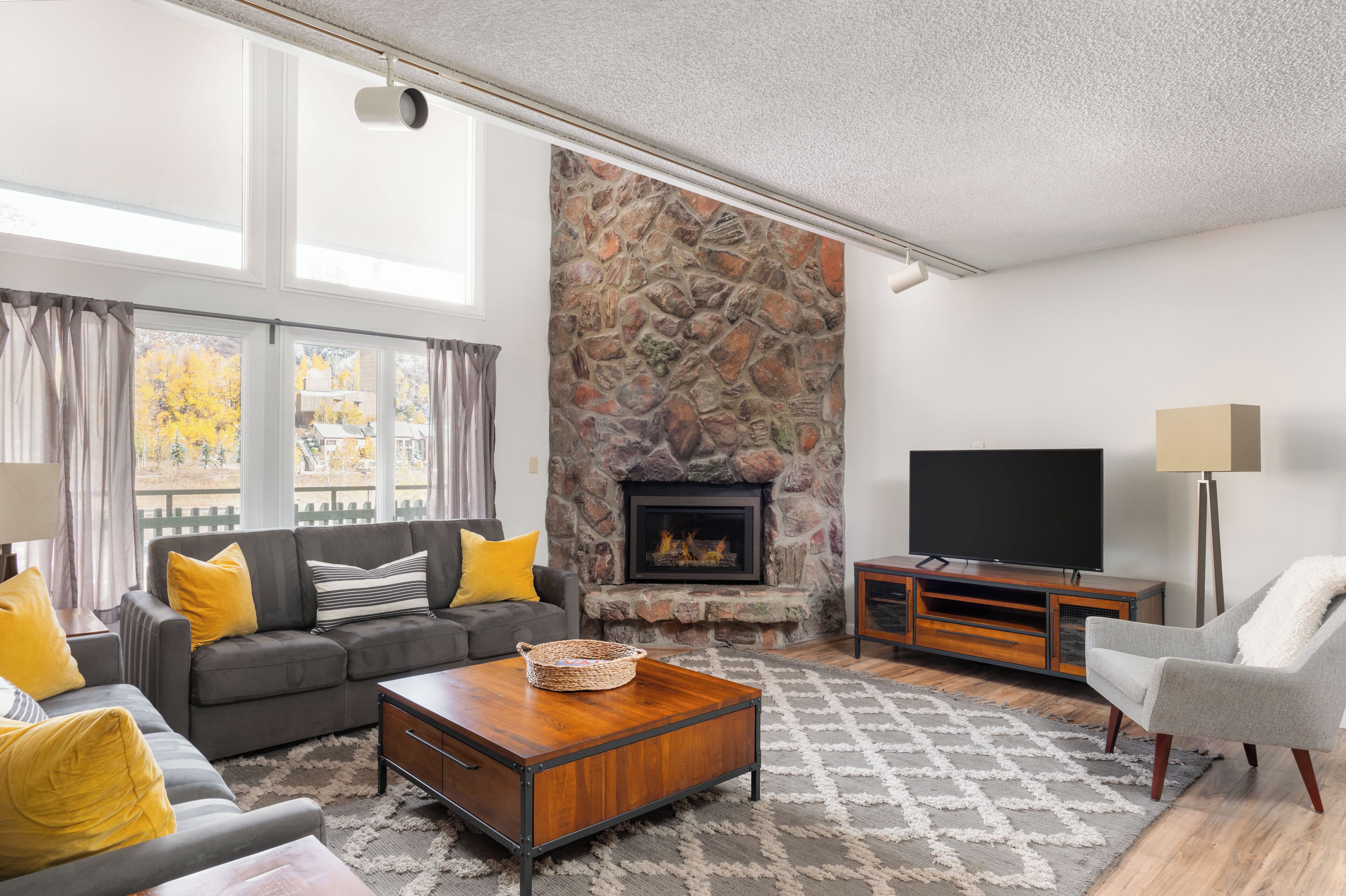 A living room with a stone fireplace, a sofa set, a television, and a coffee table.
