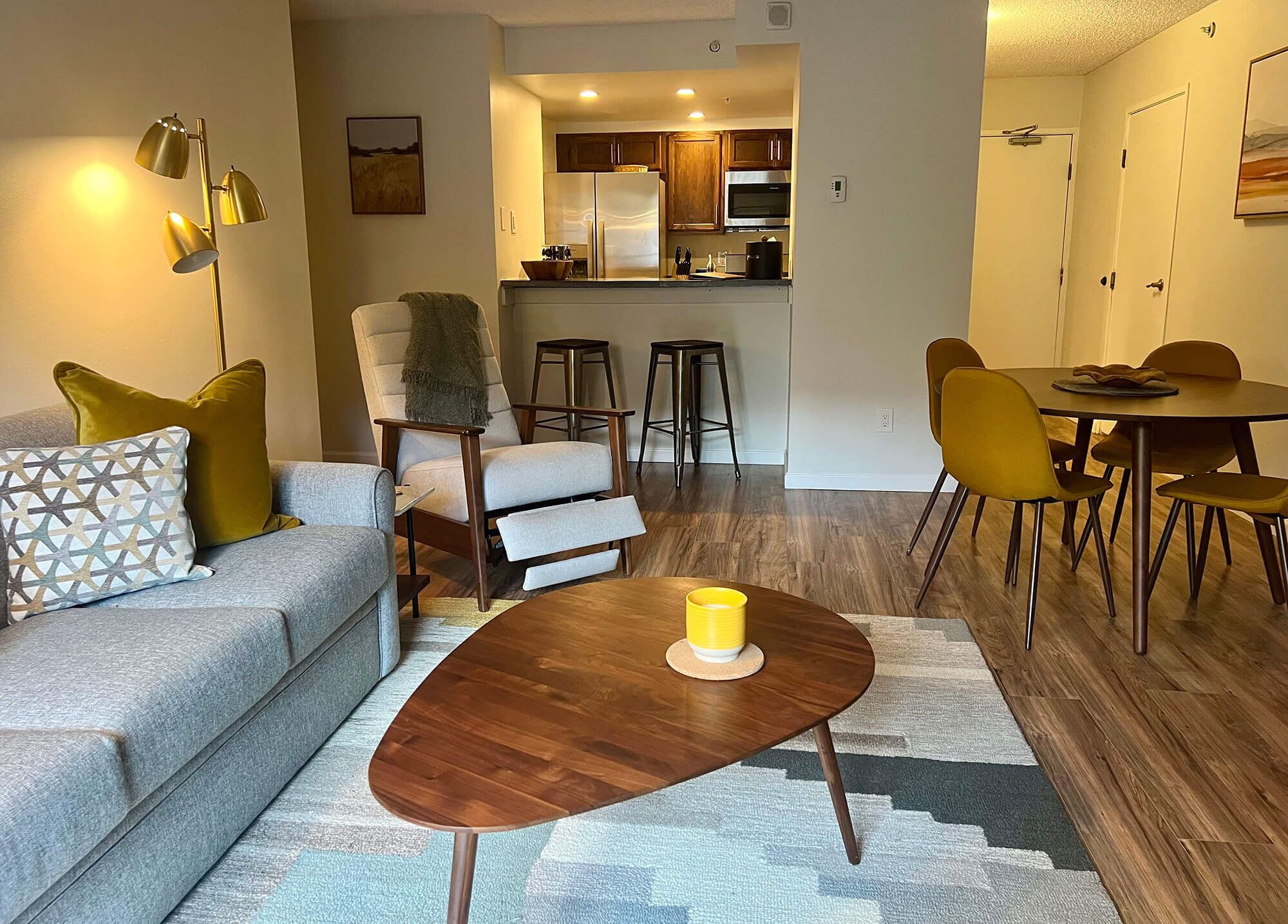 A modern living room with a sofa, armchairs, a coffee table, and a dining area with chairs and a table.