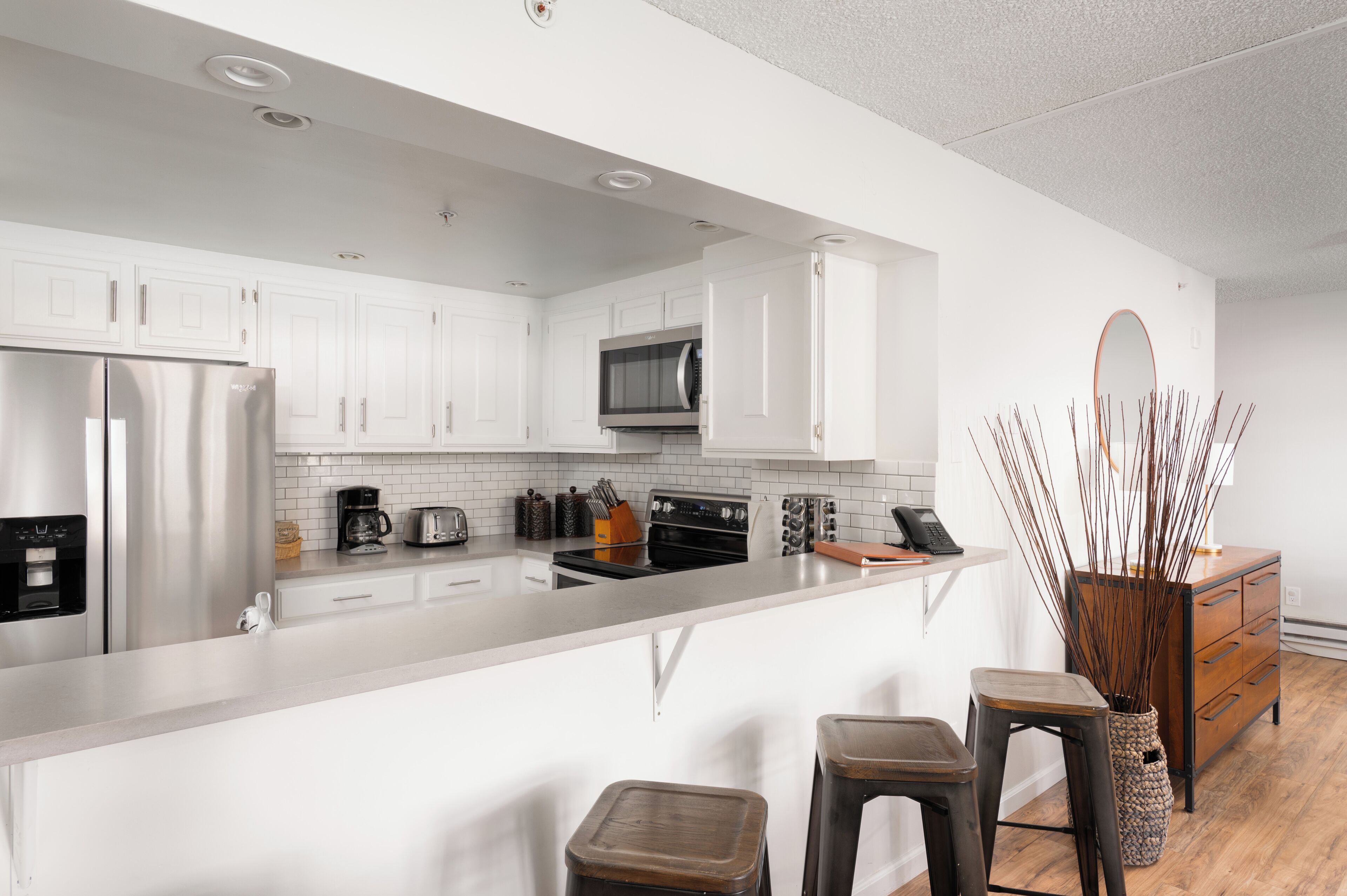 A modern kitchen with white cabinets, stainless steel appliances, and a central island with stools.