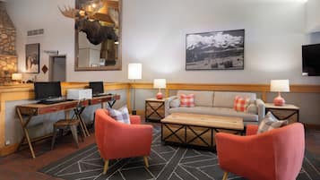 A cozy hotel lobby with a fireplace, a mounted moose head, a sofa, and a television.