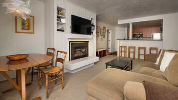 A living room with a fireplace, a television, a dining table with chairs, and a sofa.