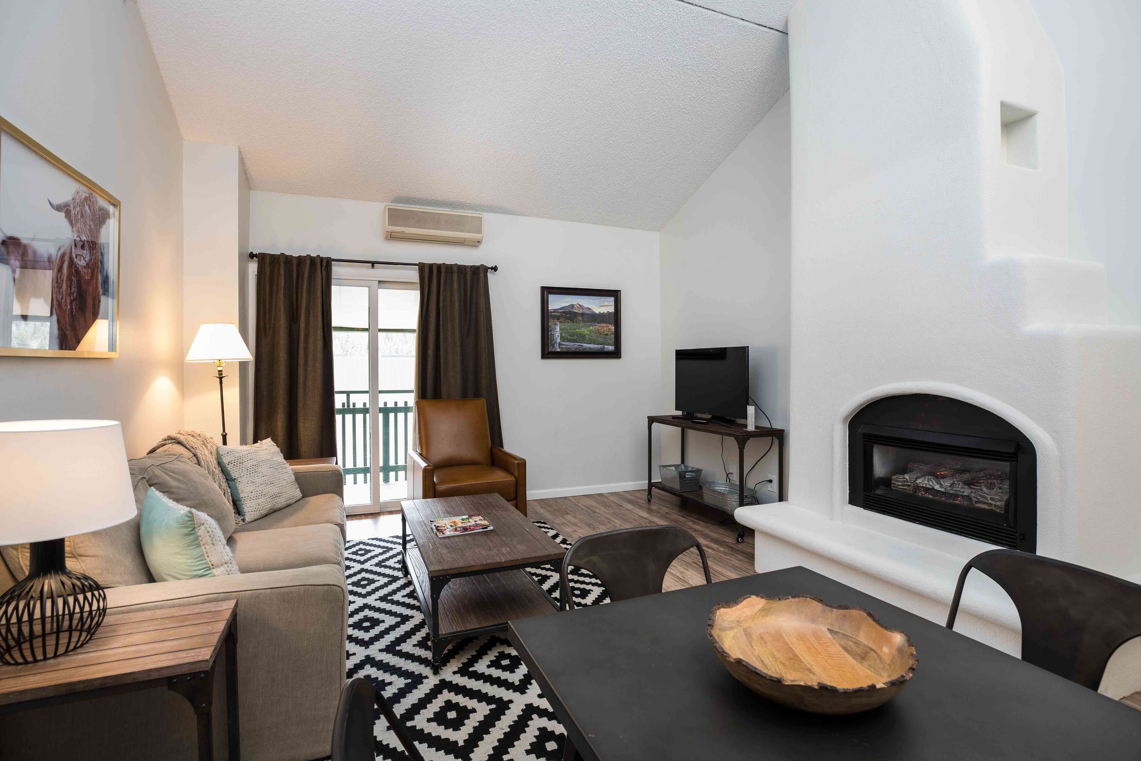 Un salon moderne comprenant un canapé, des fauteuils, une table basse et une cheminée.