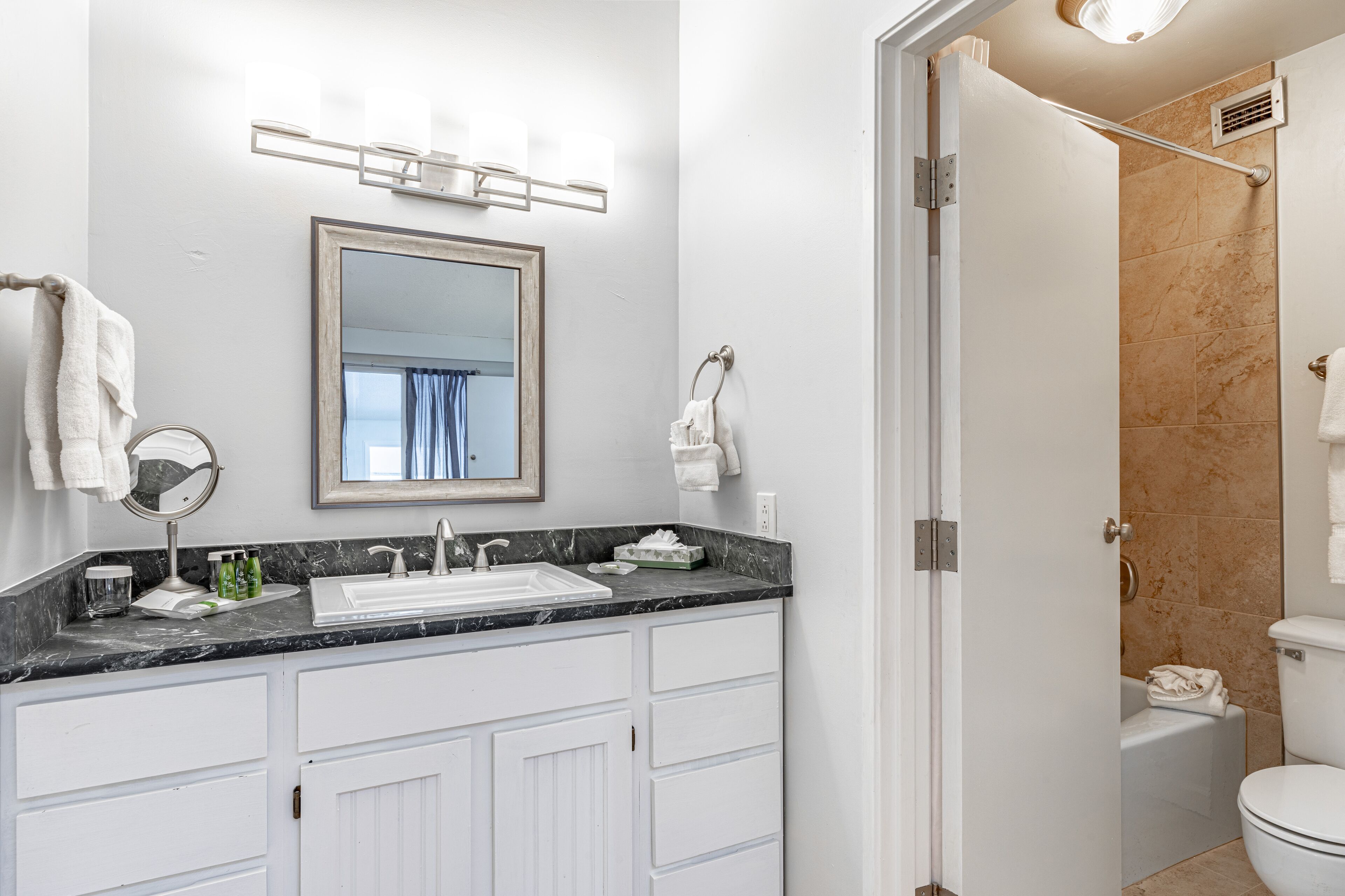 A modern bathroom with a white vanity, a large mirror, and a shower area.