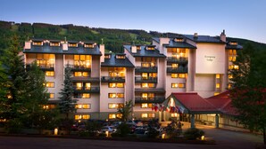 Un hotel de varios pisos con balcones, entrada con techo rojo y un cartel que dice "Evergreen Lodge".