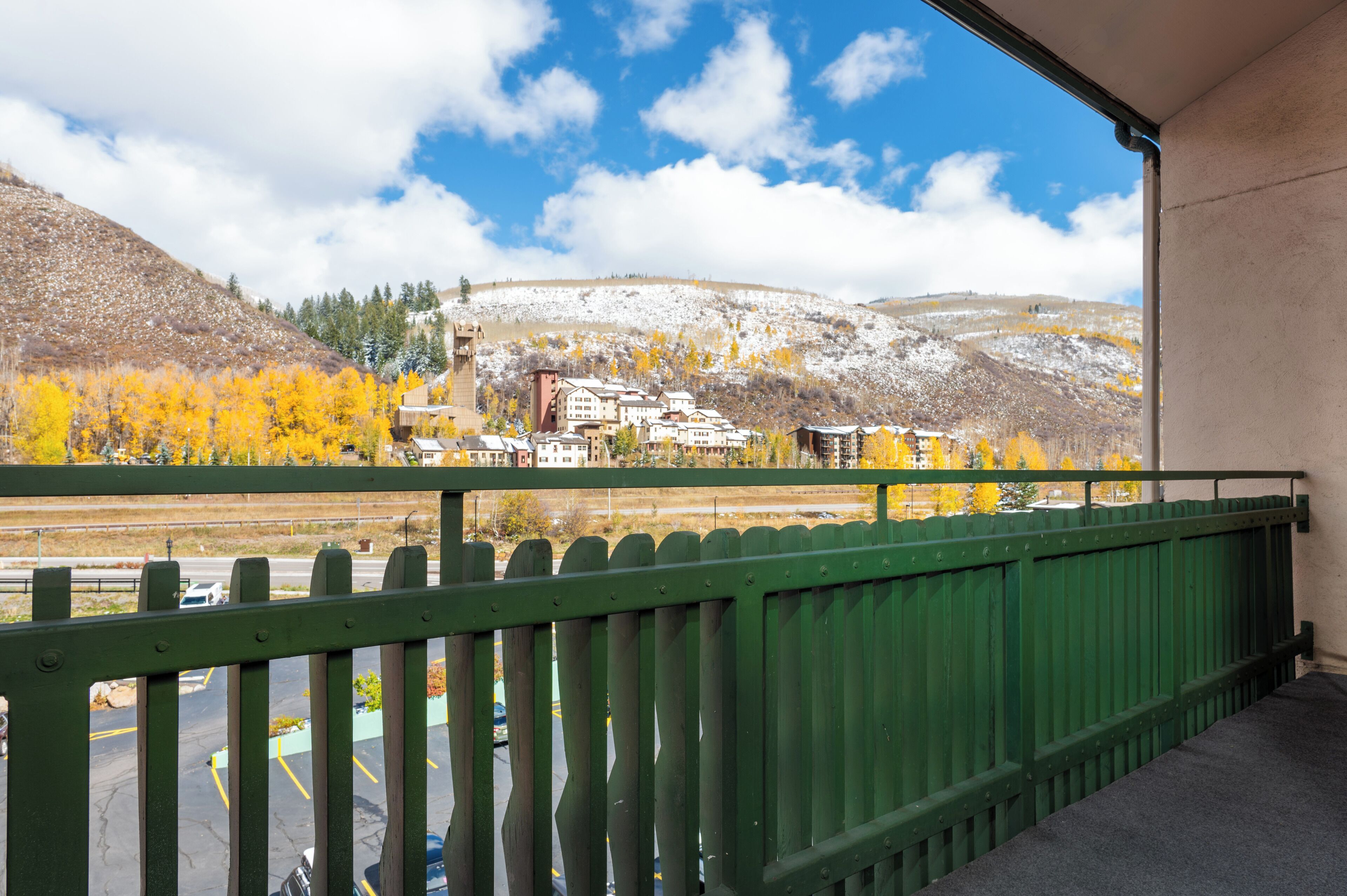 A balcony with a view of a town, a train track, and a snow-covered hill.