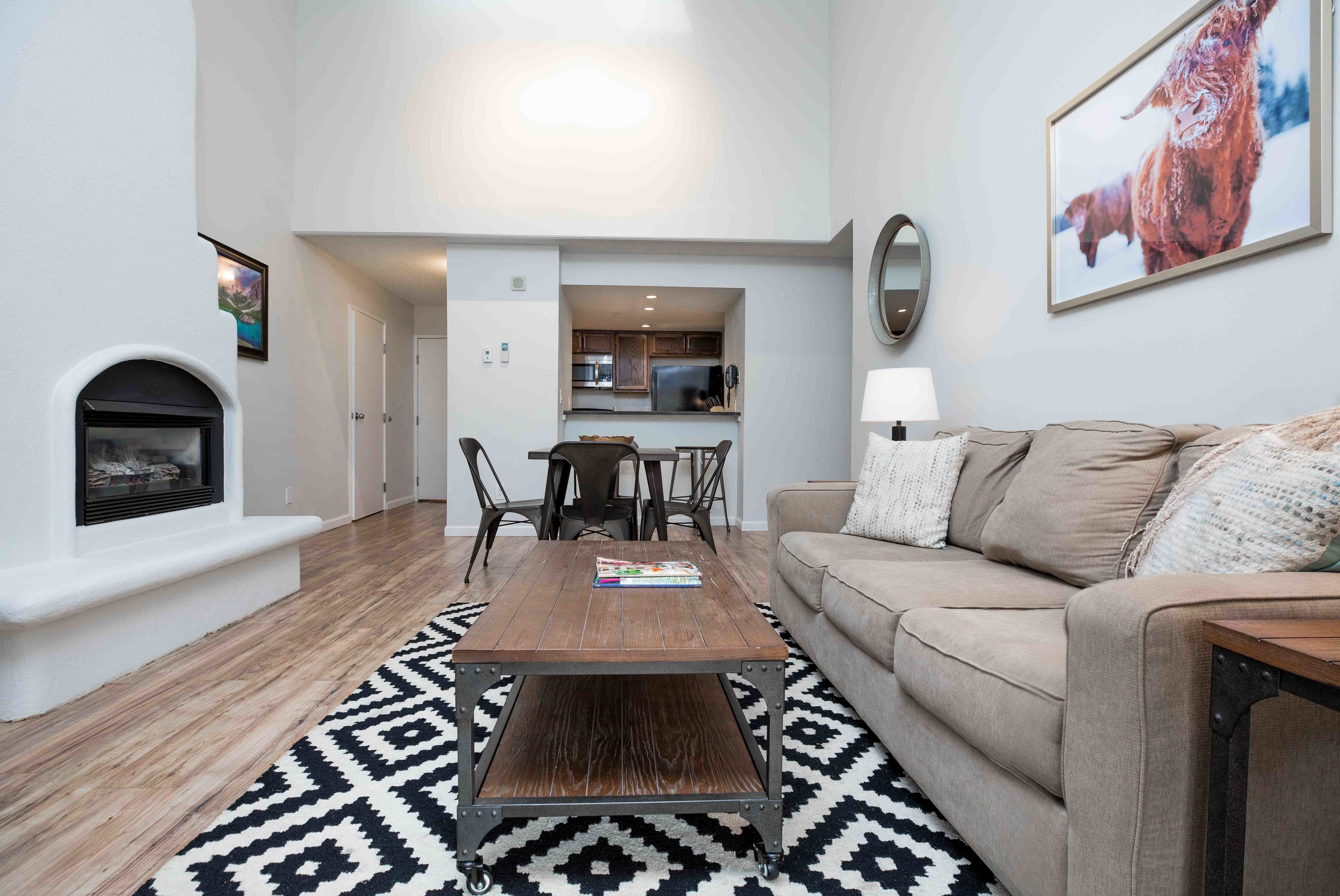 A modern living room with a fireplace, a dining table, and a sofa.