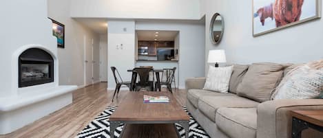 A modern living room with a fireplace, a dining table, and a sofa.