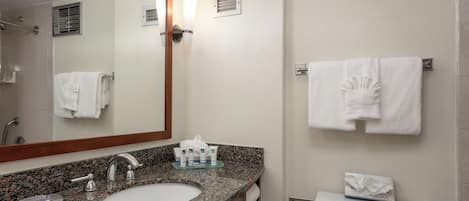 Un baño con lavamanos de encimera de granito, espejo, toallero y retrete.