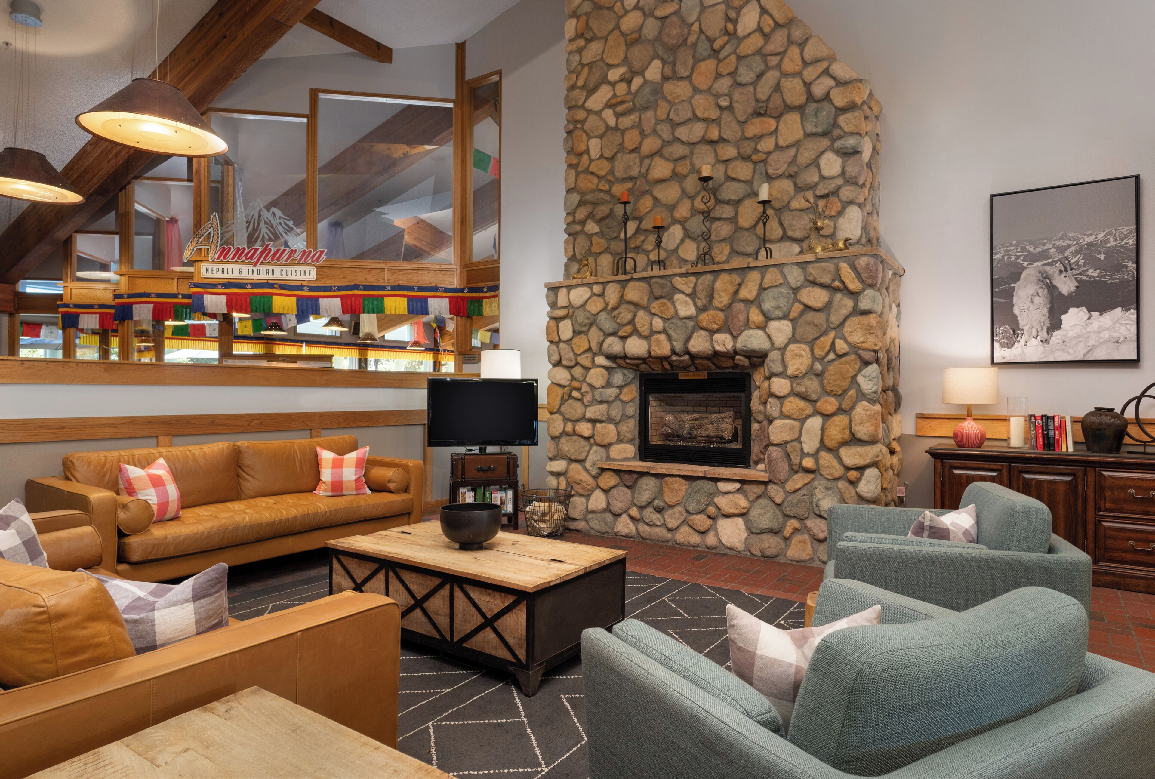 A cozy living area with a stone fireplace, comfortable seating, and a television.