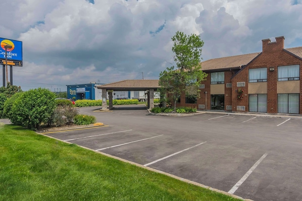 A Comfort Inn with a parking lot, a covered outdoor seating area, and a brick building with windows.
