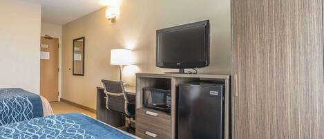 Habitación de hotel con dos camas, televisión, microondas, refrigerador, escritorio con silla y armario.