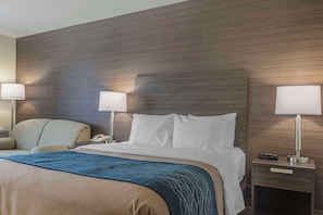 A hotel room with a bed, two bedside lamps, a nightstand with a phone, and a chair.