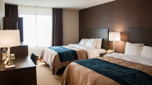 Habitación de hotel con dos camas, un escritorio, una lámpara, un teléfono y una ventana con cortinas.