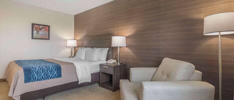 A hotel room with a bed, bedside tables, a lamp, and a chair.