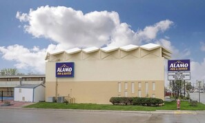 A hotel with a flat roof, beige exterior walls, and two prominent signs advertising the Alamo Inn & Suites. - Alamo Inn & Suites (Gillette)