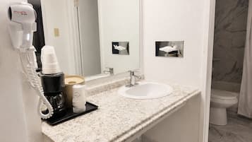Un baño con lavamanos blanco, un espejo, un secador de pelo y un inodoro.