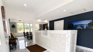 A reception area with a marble floor, a reception desk, and a view of a lake through the window. - Alamo Inn & Suites (Gillette)