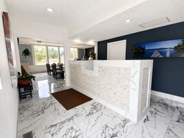 A reception area with a marble floor, a reception desk, and a view of a lake through the window.