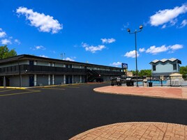 A motel with a parking lot, a swimming pool, and a small building with a satellite dish.
