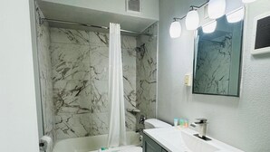 A bathroom with a bathtub, toilet, and vanity. - Alamo Inn & Suites (Gillette)