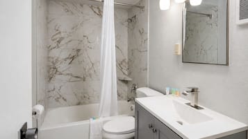 Une salle de bain avec une baignoire, des toilettes et un meuble-lavabo avec un miroir.