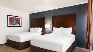 A hotel room with two beds, a nightstand, a lamp, and a framed picture on the wall. - Alamo Inn & Suites (Gillette)