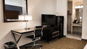 A hotel room with a desk, chair, television, microwave, and a small kitchenette. - Alamo Inn & Suites (Gillette)