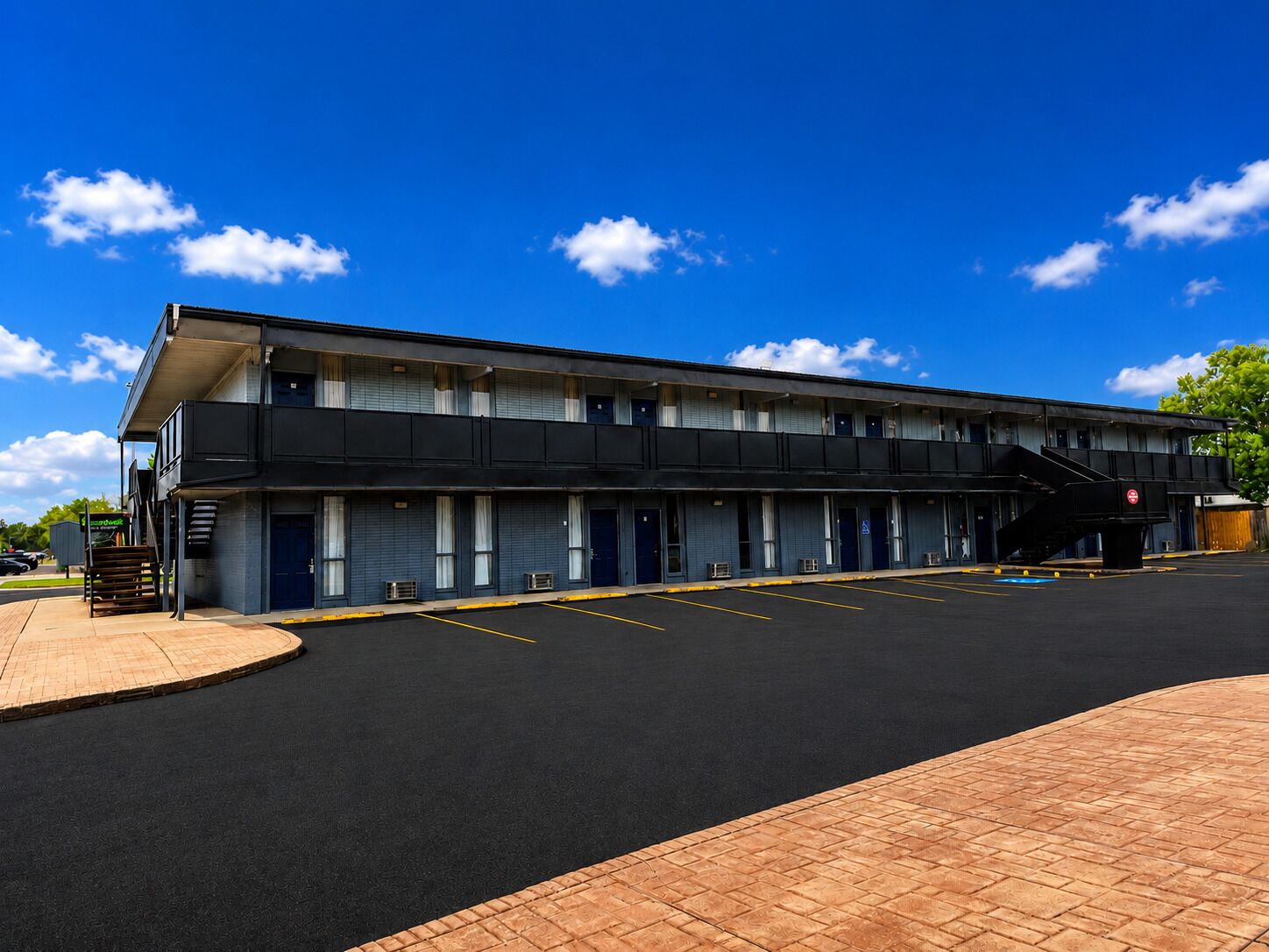 Um motel de dois andares com estacionamento e galeria coberta.
