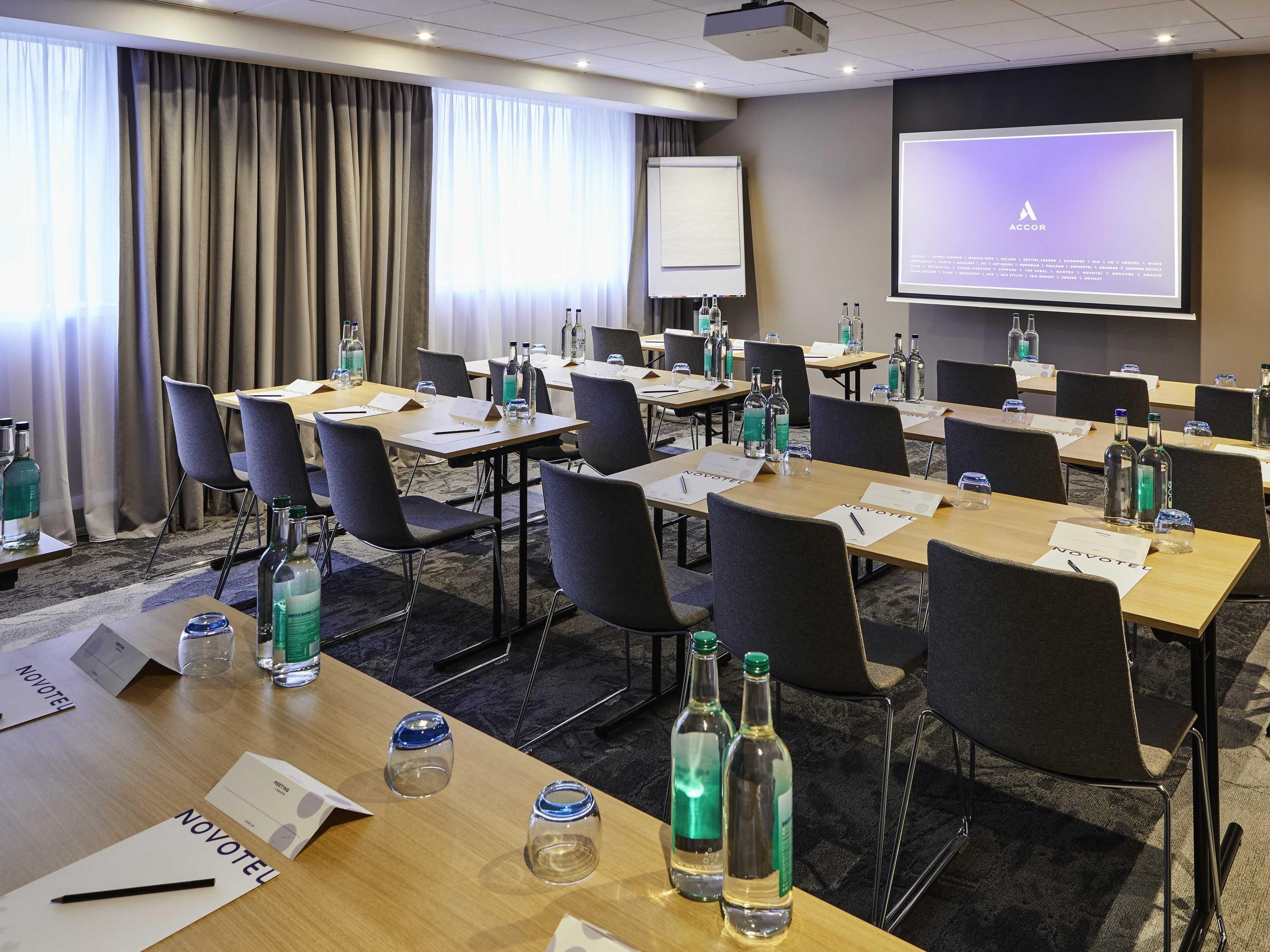 A conference room with tables, chairs, name cards, and water bottles.