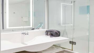 A modern bathroom with a white sink, a large mirror, and a glass shower enclosure.