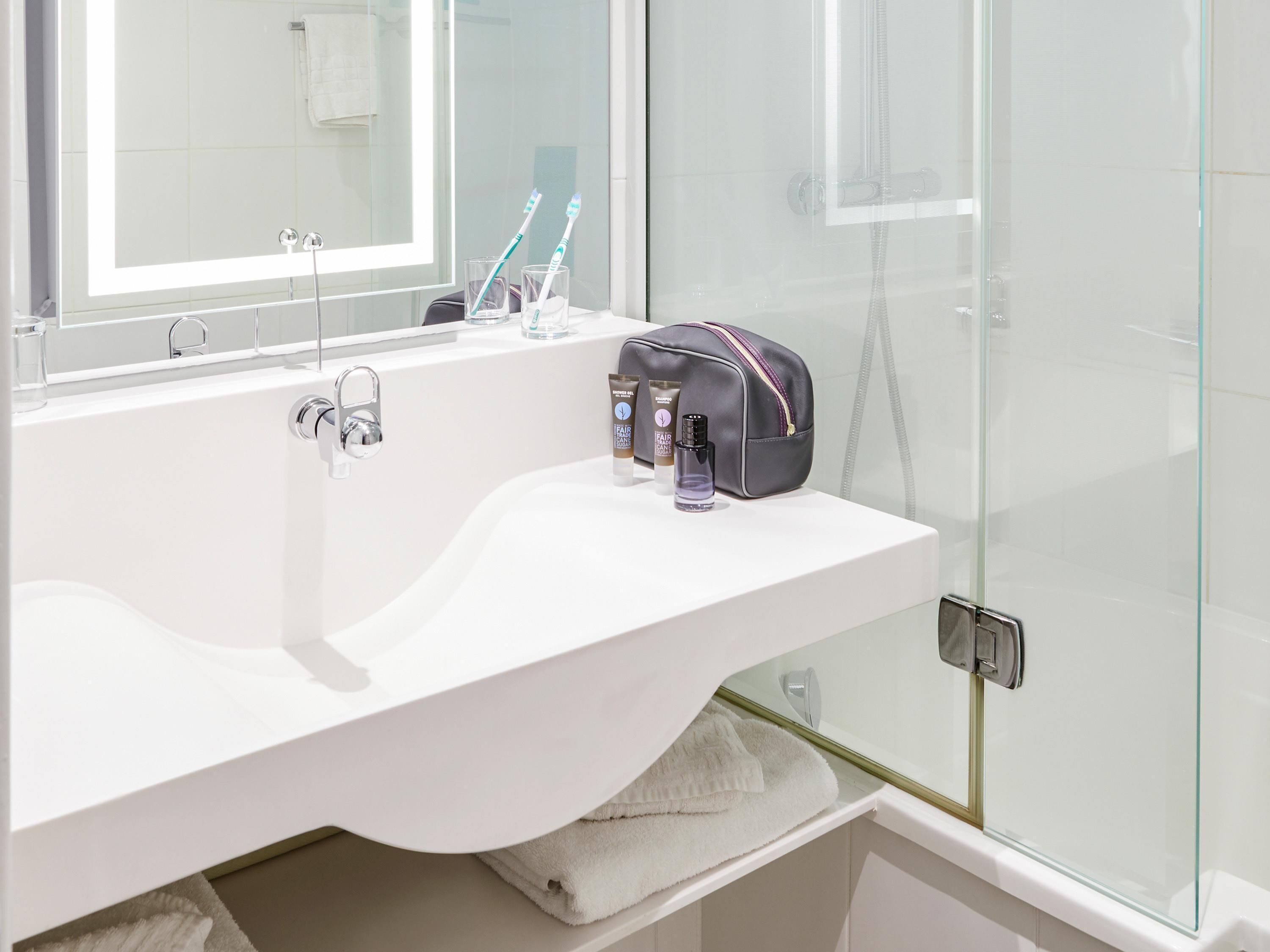 A bathroom with a white sink, a mirror, and a glass shower enclosure.