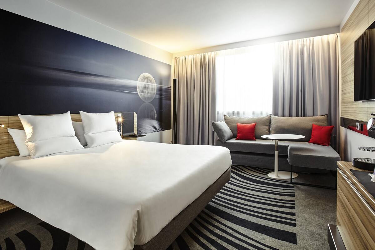Een hotelkamer met een groot bed, een slaapbank, een kleine tafel en een televisie.