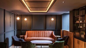 Ein modernes Interieur mit einem Ledersofa, zwei Sesseln, einem kleinen Tisch und einer Holzkassette mit Pflanzen.