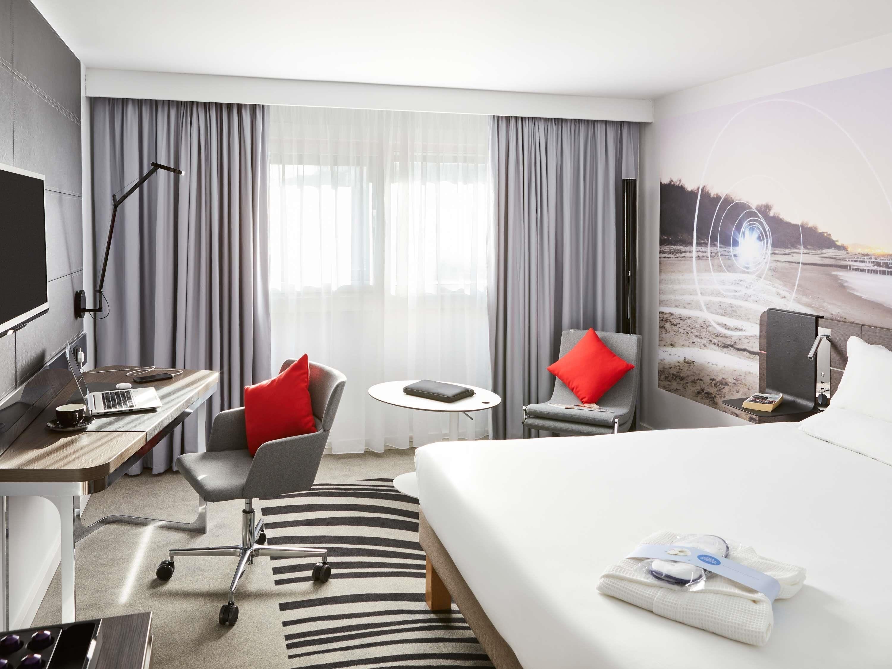 Habitación de hotel con cama, escritorio, silla y televisor.