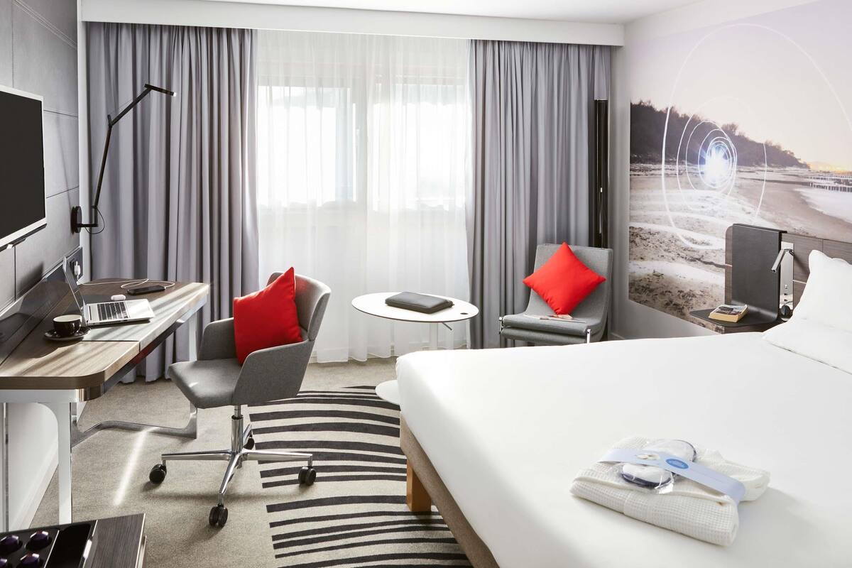 Een hotelkamer met een bed, bureau, stoel en een televisie.