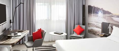 Une chambre d’hôtel équipée d’un lit, d’un bureau, d’une chaise et d’un téléviseur.