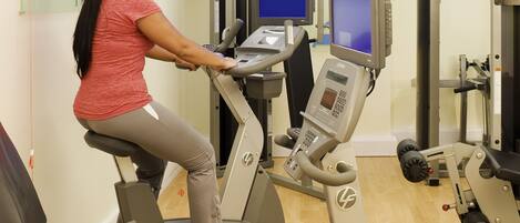 A woman using a Life Fitness elliptical machine in a gym with various exercise equipment and a sign that reads "In Balance".