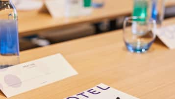 A hotel room with a wooden table, a name card, a pen, and a glass of water.