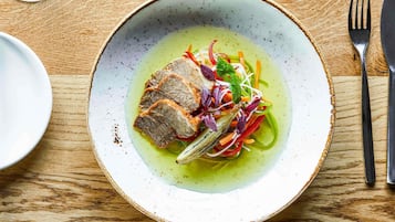 A plate of food with a meat dish and vegetables on a wooden table.