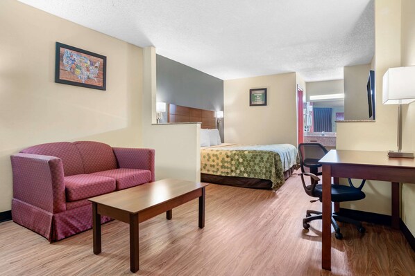A hotel room with a bed, a sofa, a desk, a chair, and a small table.