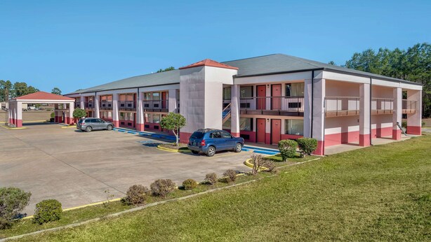 A modern hotel with a central courtyard, multiple parking spaces, and a covered outdoor seating area.