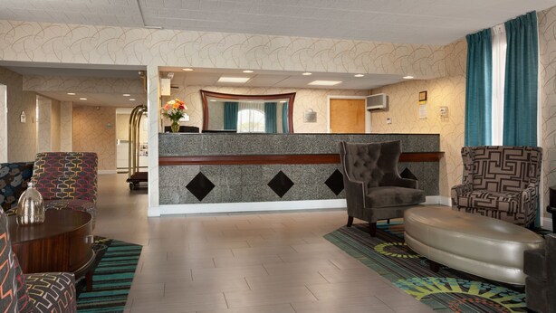 A hotel lobby with patterned walls, a reception desk, and modern seating arrangements. - Days Inn by Wyndham Reading Wyomissing (Wyomissing)
