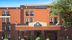 A Days Inn building with a brown facade, arched windows, and a sign above the entrance. - Days Inn by Wyndham Reading Wyomissing (Wyomissing)