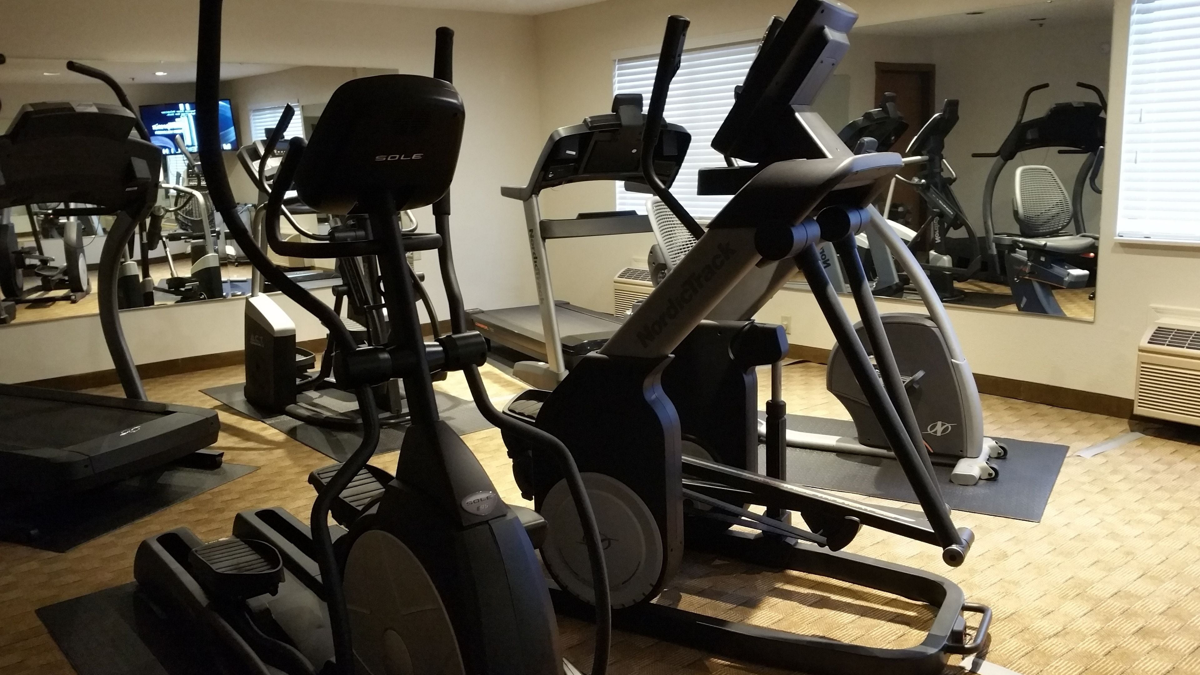A gym with various exercise equipment including treadmills, stationary bikes, and elliptical machines.