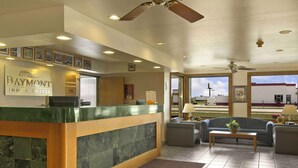 A hotel reception area with a reception desk, seating area, and a view of the outside. - Baymont by Wyndham Tuscola (Tuscola)