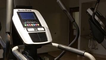 A NordicTrack elliptical machine with a digital display and control panel, positioned on a black mat in a gym setting.