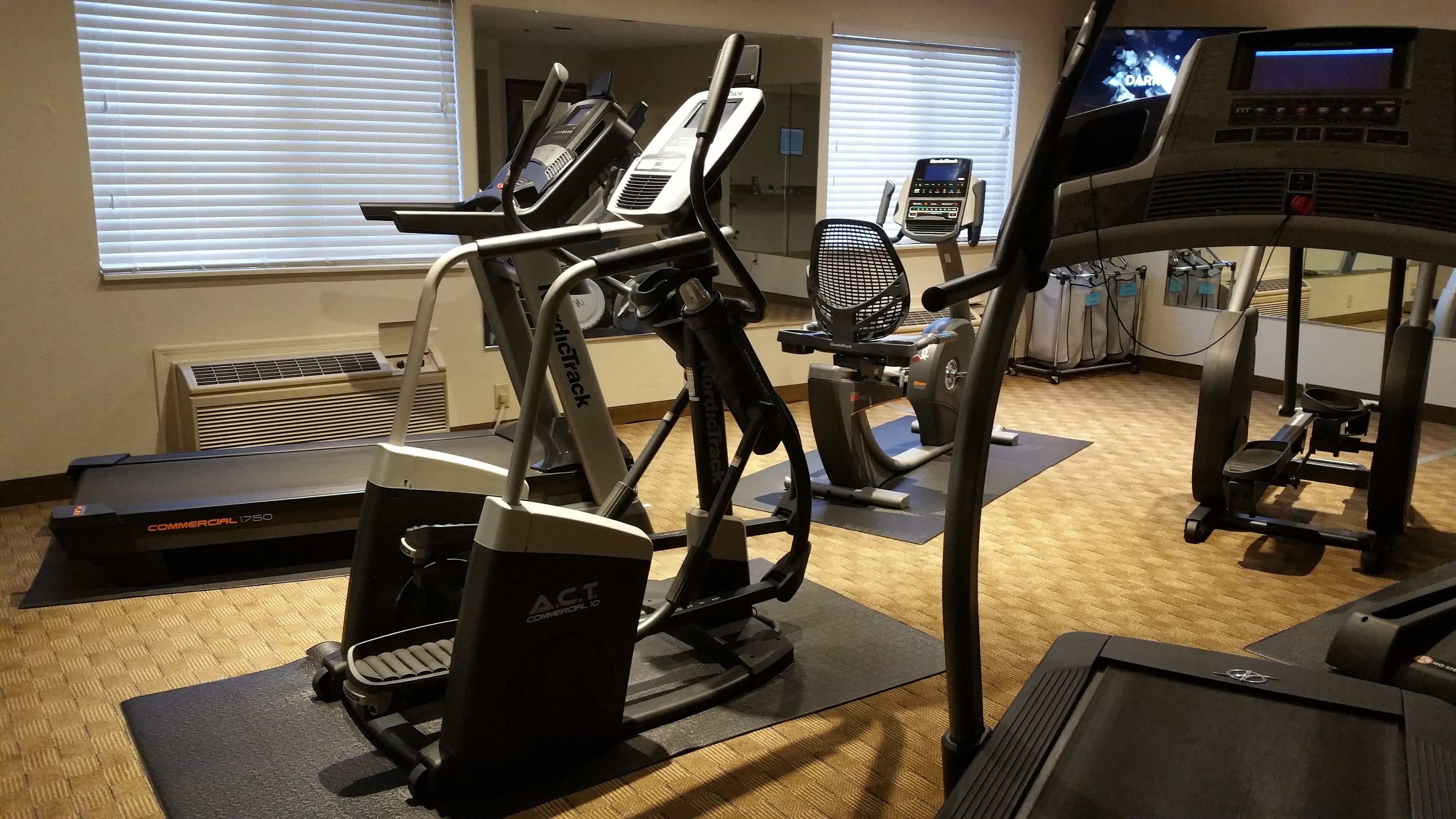 Une salle de sport équipée de divers appareils d’exercice, notamment des tapis de course, des vélos elliptiques et des appareils de musculation.