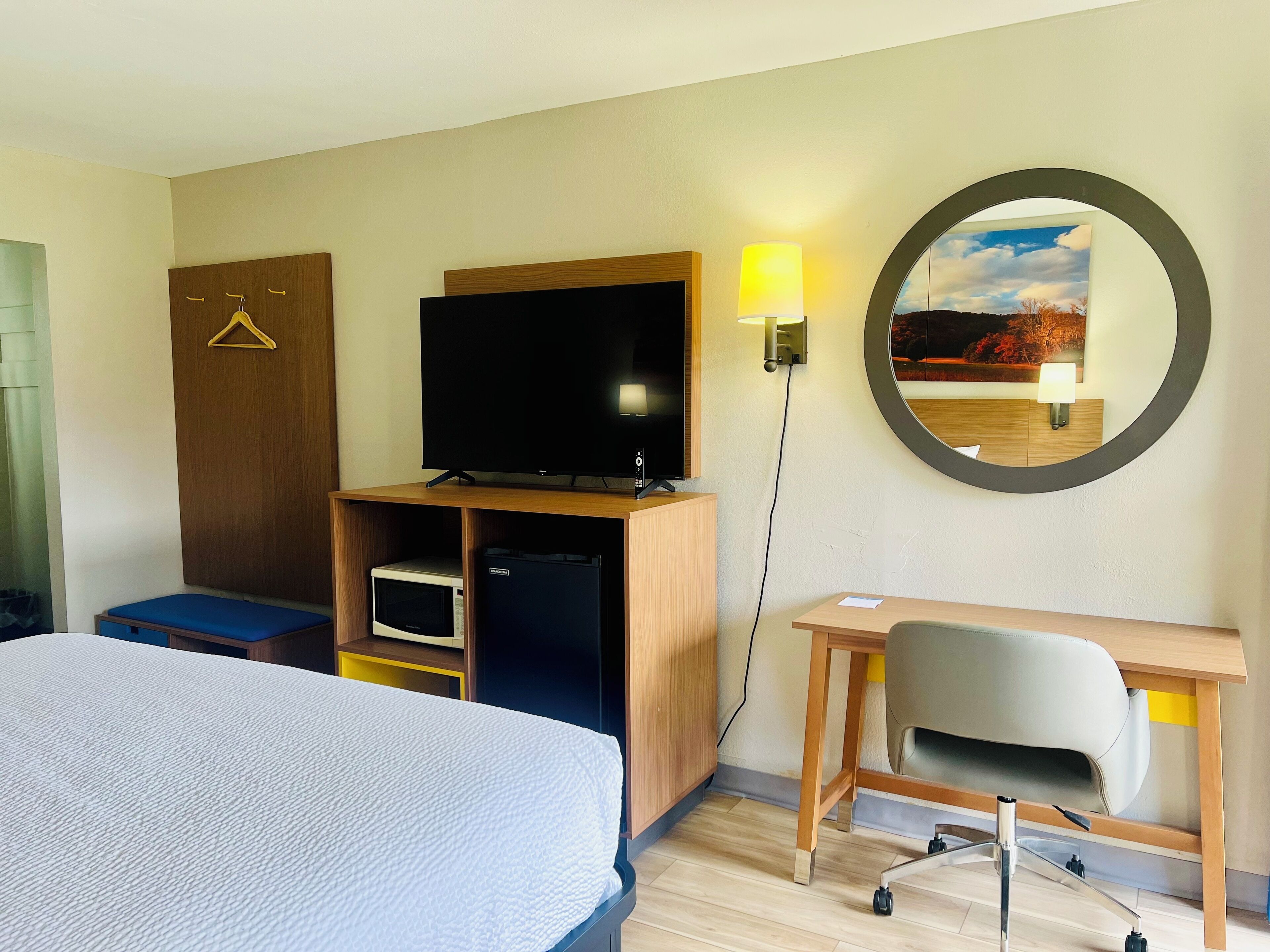 Une chambre d’hôtel comprenant un lit, un bureau, une télévision, une armoire et un miroir.